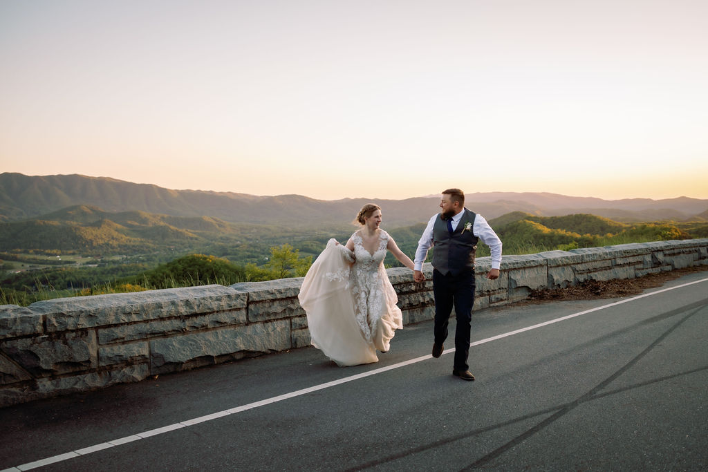 bride and groom holding hands and running across the parkway during sunset photographed by Gatlinburg photographers