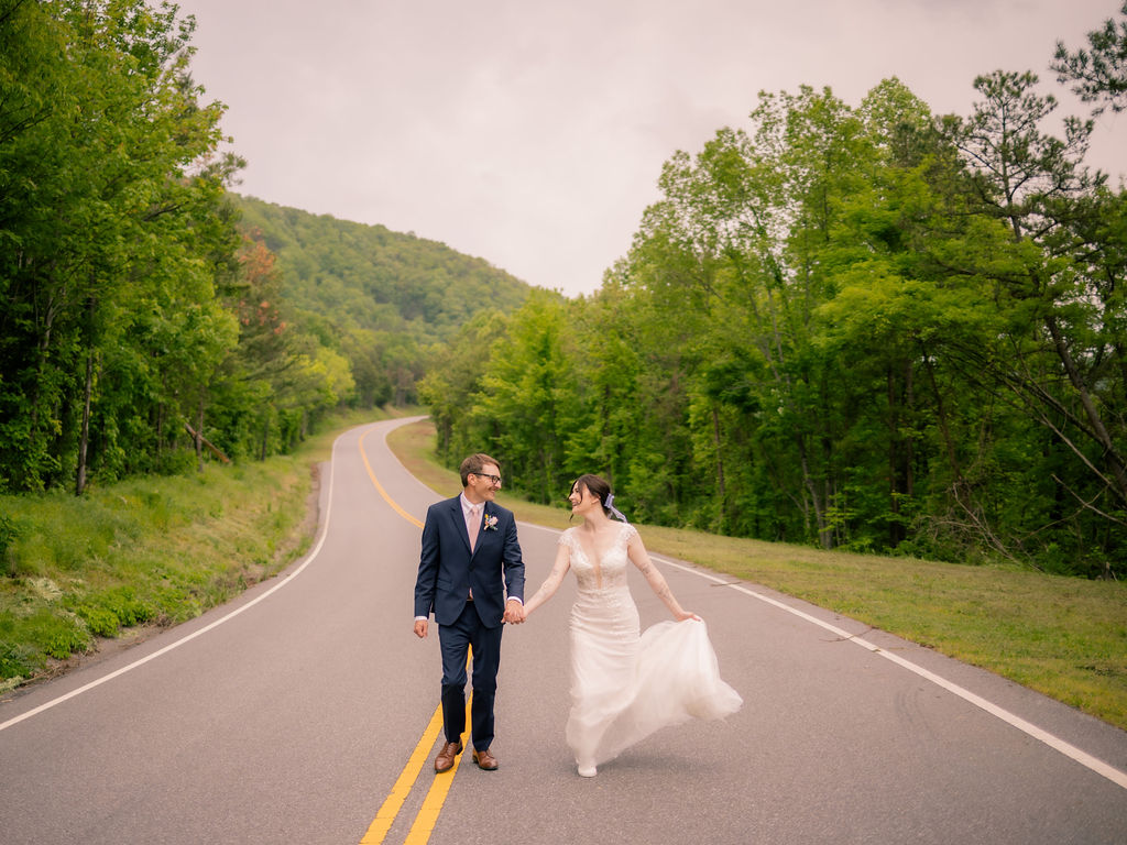 Foothills Parkway Elopement with bride and groom holding hands and smiling at one another as they walk down the parkway together