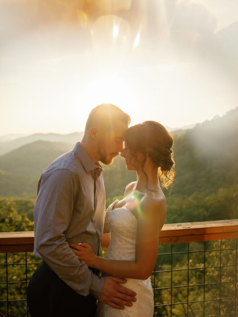 Smoky Mountain elopement with bride and groom embracing as the sun shines through the trees and over the hills