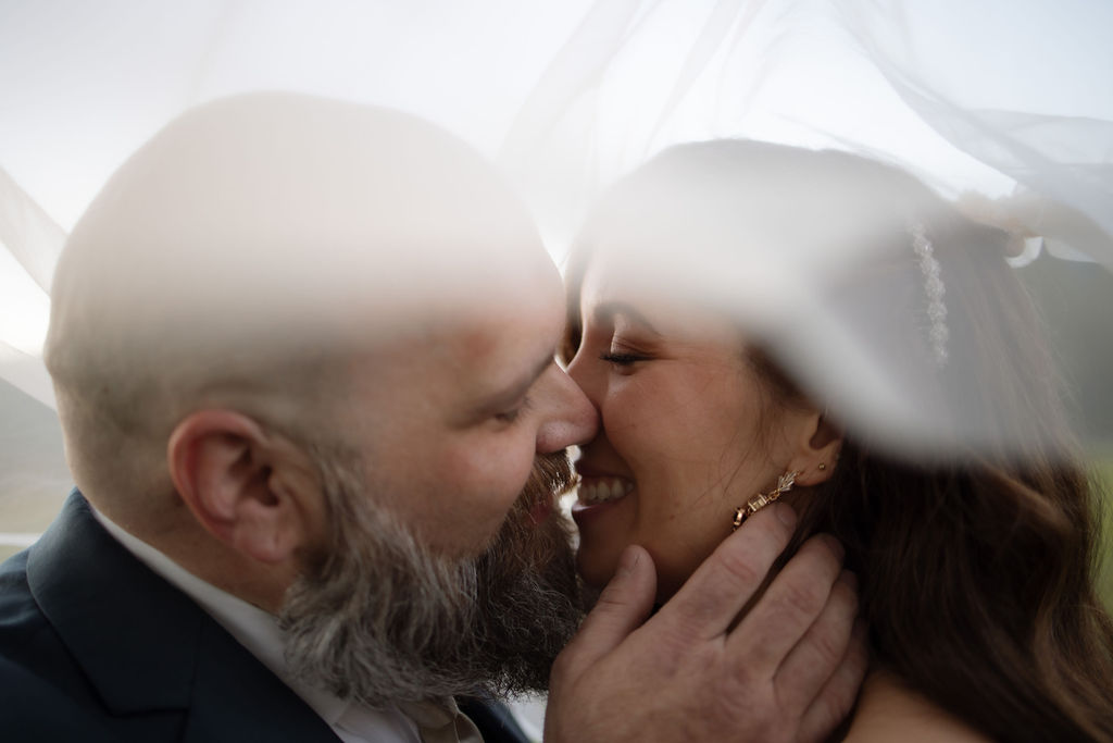 An intimate close-up of the bride and groom sharing a loving moment beneath a softly flowing veil, their joy and connection beautifully captured by a Gatlinburg photographer during their Cades Cove elopement.