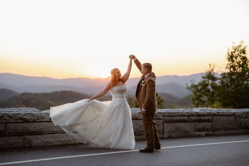 Foothills Parkway elopement with couple dancing at sunset on the road with the Smoky Mountains in the distance captured by photographers in gatlinburg tn