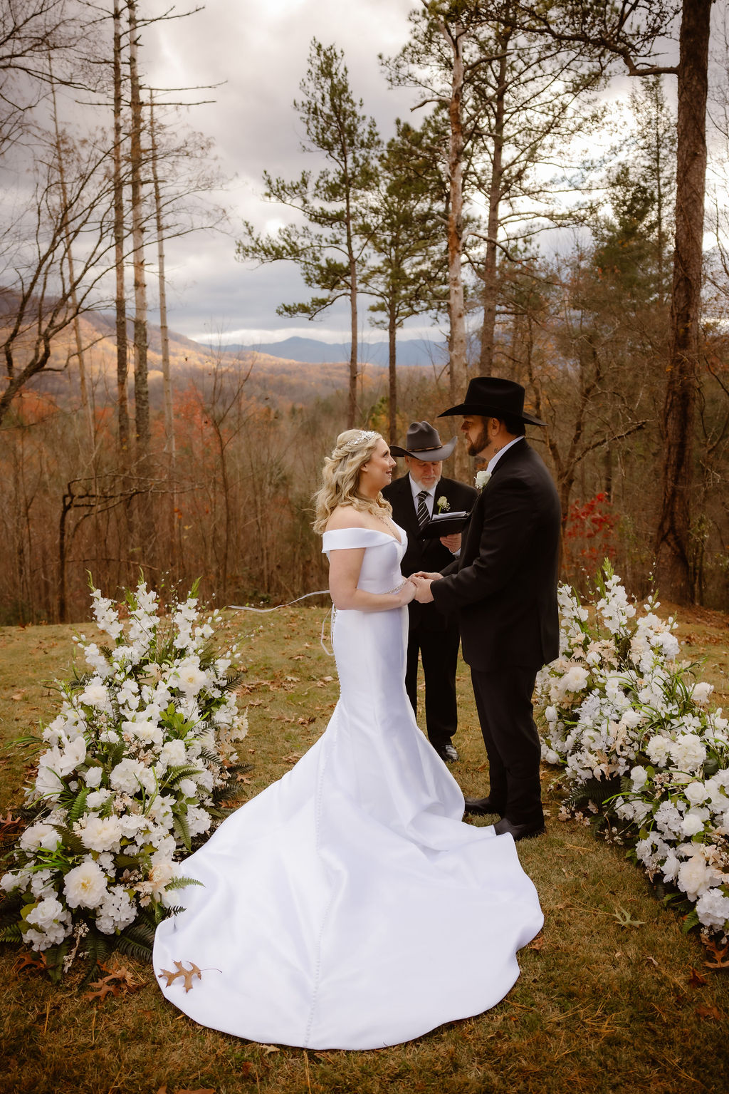 bride and groom holding hands during their outdoor wedding ceremony at Roosevelt Lodge Gatlinburg Venue with the mountains in the distance