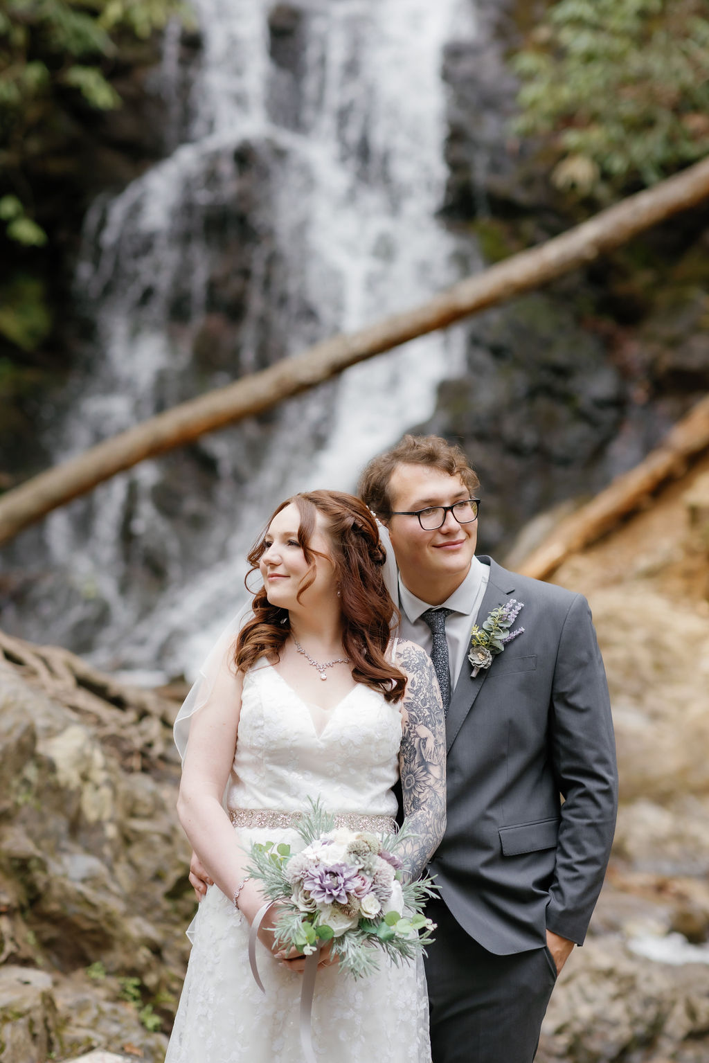 Bride and groom stand closely together in front of a waterfall during their waterfall elopement in Tennessee, captured by Gatlinburg photographer.