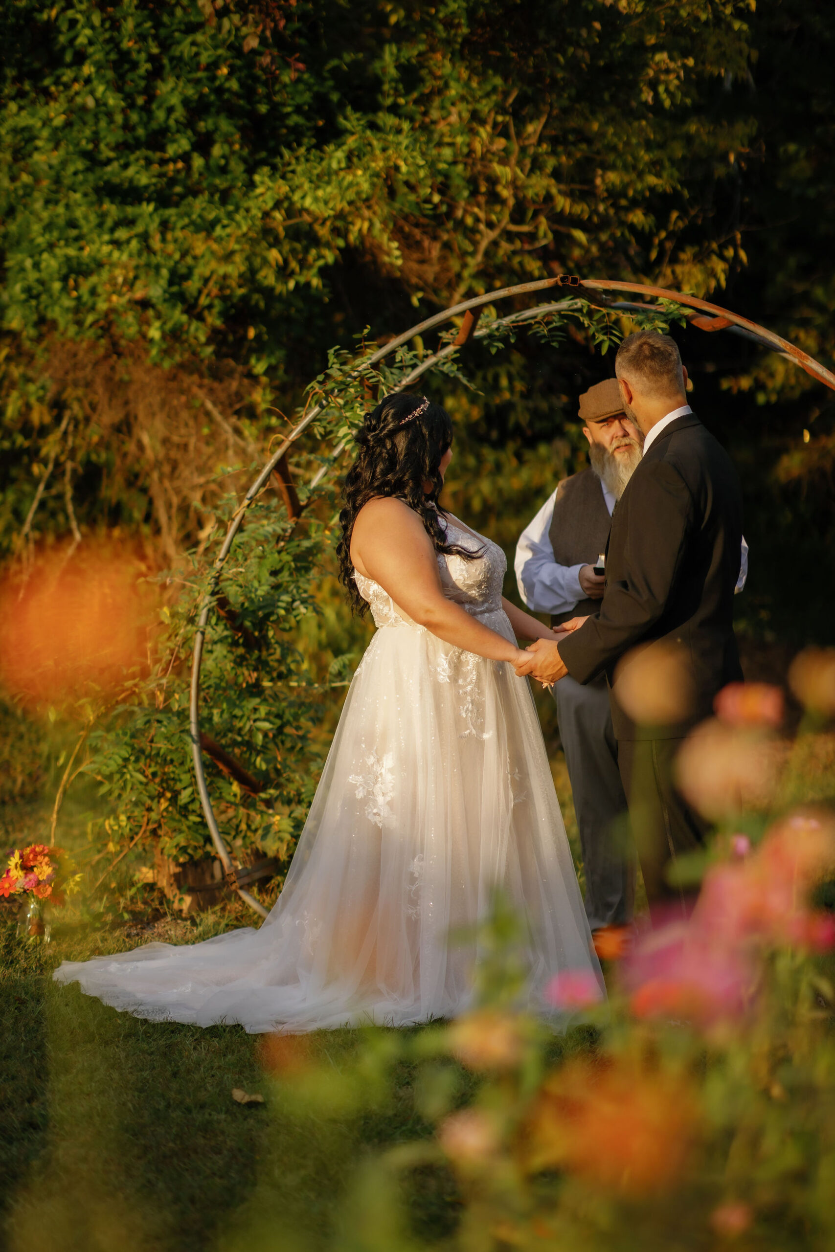 Bride and groom exchange vows under a rustic arch surrounded by vibrant blooms at Wildflower Field Wedding Venue, perfect for couples who want to elope to Gatlinburg.