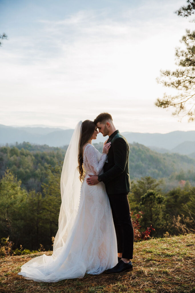 Winter Smoky Mountains elopement with a bride and groom standing forehead to forehead against a mountain backdrop in the foothills