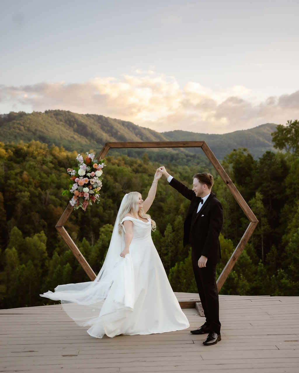 Couple sharing a joyful moment and dancing together at a dreamy venue in the Smokies, surrounded by breathtaking mountain views and lush forest — the perfect setting for eloping to Gatlinburg.