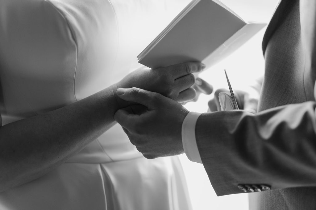 Black and white close-up of a couple holding hands and reading vows from notebooks, highlighting an intimate wedding moment captured during a Gatlinburg Winter by a local photographer.