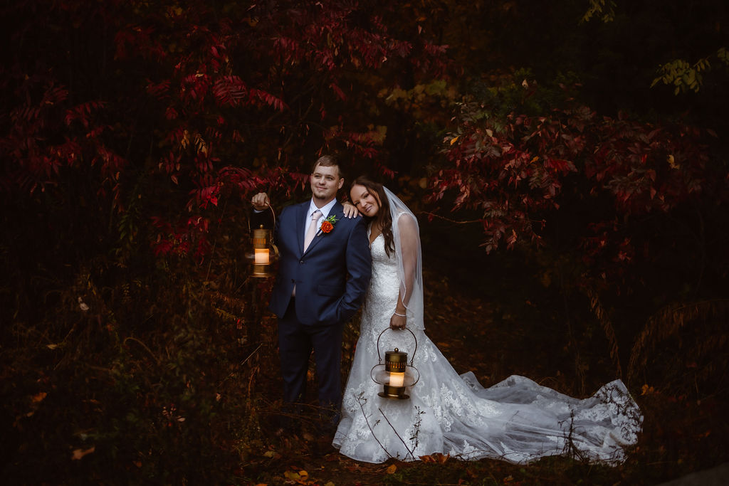 Under a canopy of deep autumn leaves, this bride and groom share a cozy moment lit by lantern glow—capturing the magic of their Gatlinburg elopement with a trusted wedding officiant.