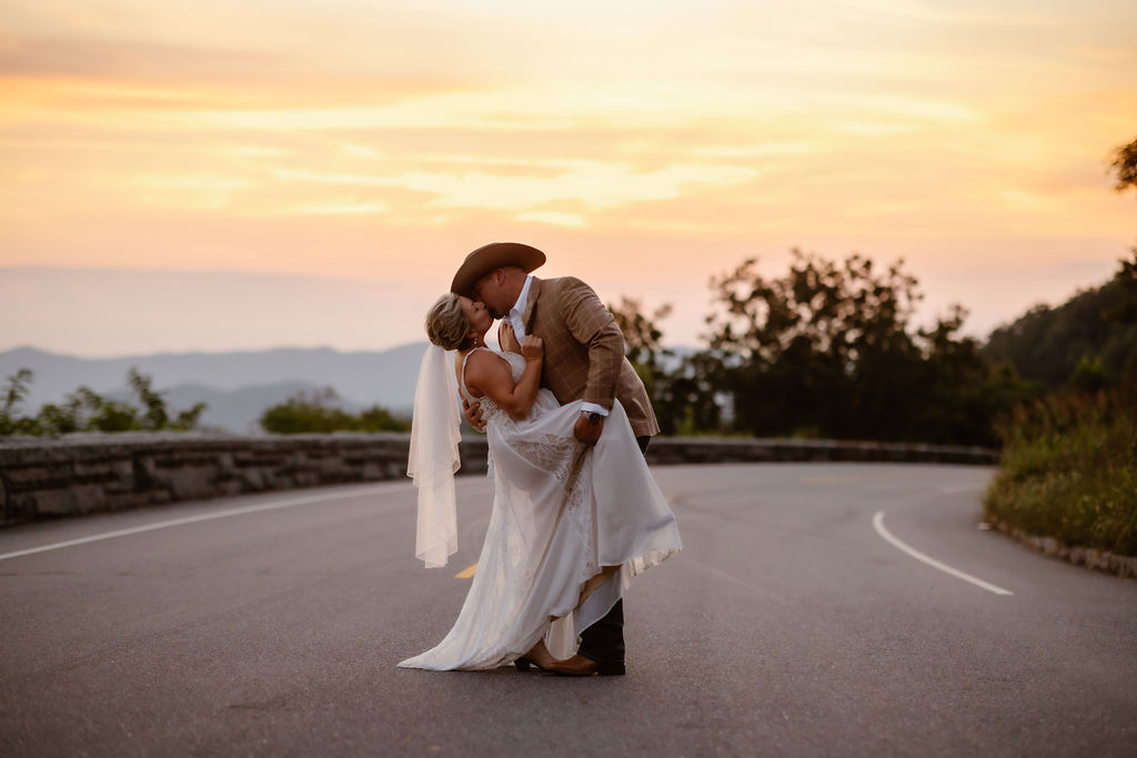 Sunset elopement at Foothills Parkway in the Smoky Mountains, with the groom dipping the bride in the middle of the scenic mountain road as golden hour light glows over the Appalachian ridgelines during a romantic Smoky Mountain elopement.