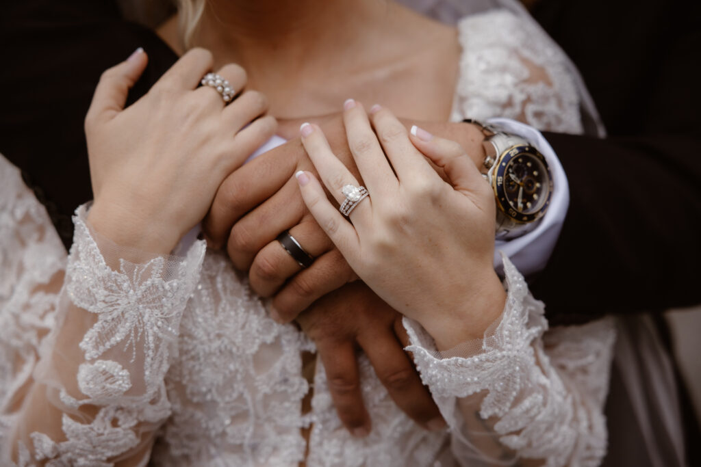Detailed wedding ring photo featuring bride and groom hands against a lace wedding dress during their eloping to Gatlinburg celebration