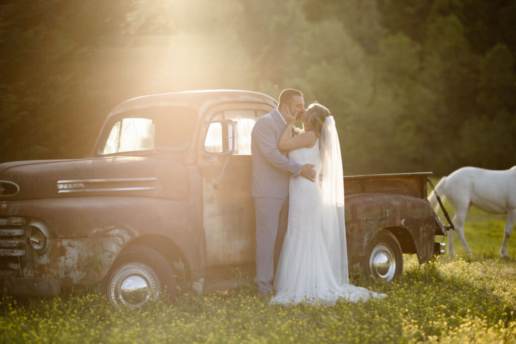 Bride and groom sharing a kiss beside a vintage truck at Honeysuckle Hills during golden hour, photographed by a smoky mountain elopement photographer.