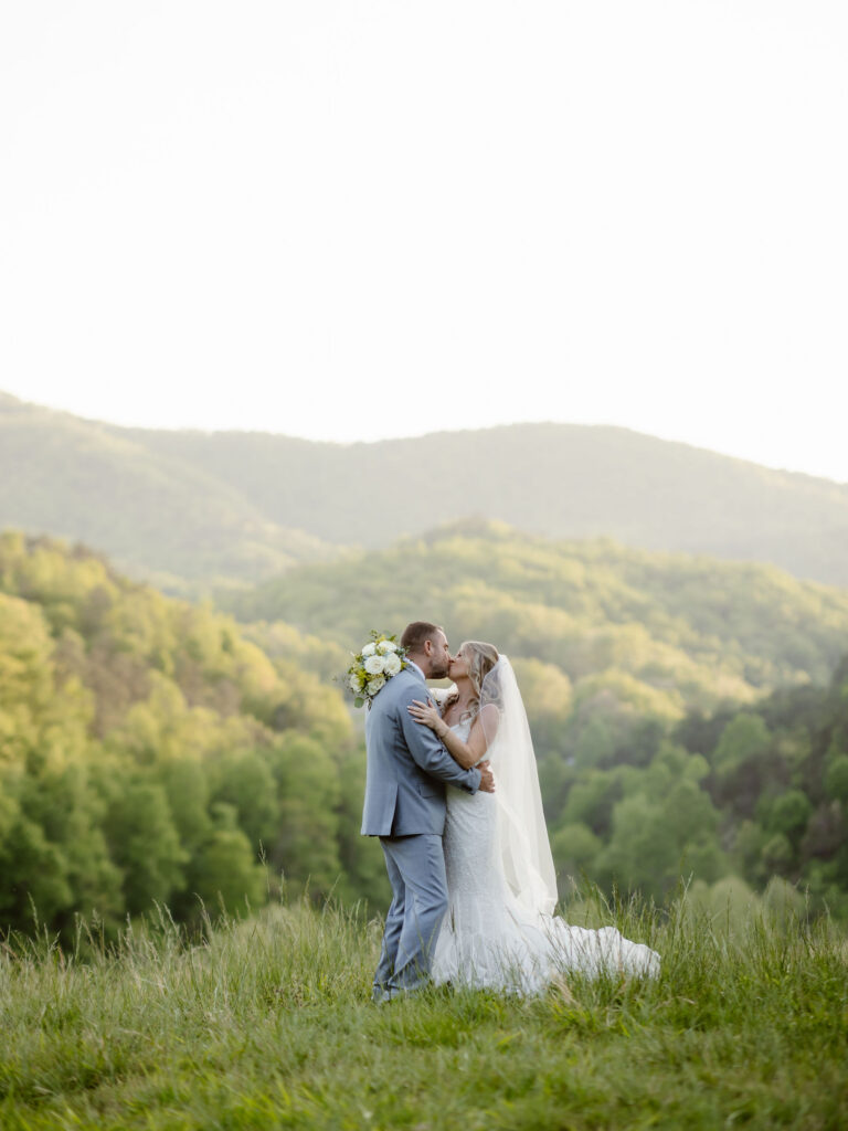 Bride and groom sharing a kiss with panoramic mountain views behind them at Honeysuckle Hills, photographed by a smoky mountain elopement photographer.
