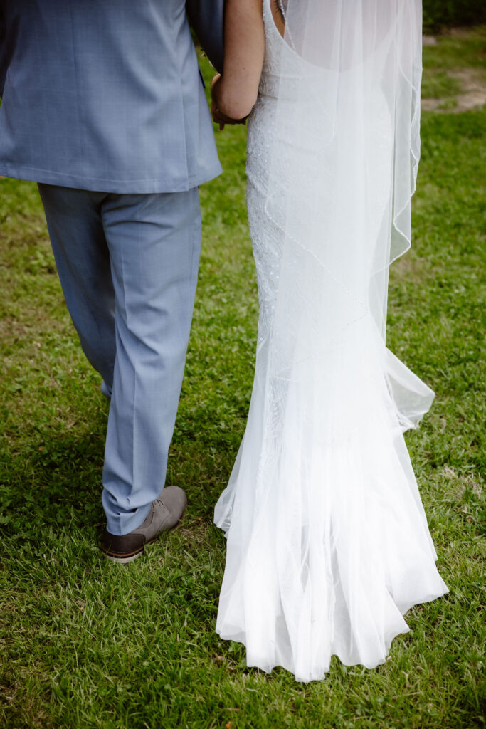 Close-up of the bride and groom walking hand in hand across the lawn at Honeysuckle Hills after their wedding ceremony.