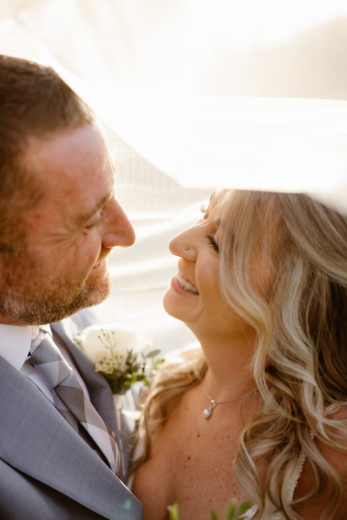 Bride and groom smiling beneath the bride's veil during golden hour, captured by a smoky mountain elopement photographer.