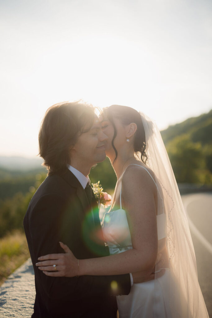 Bride kisses the groom’s cheek in warm golden-hour light during their Foothills Parkway elopement in the Smoky Mountains.
