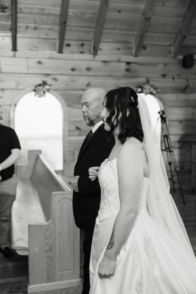 Bride stands beside a family member before walking down the aisle inside the rustic Little Log Chapel in Gatlinburg for her Gatlinburg elopement.