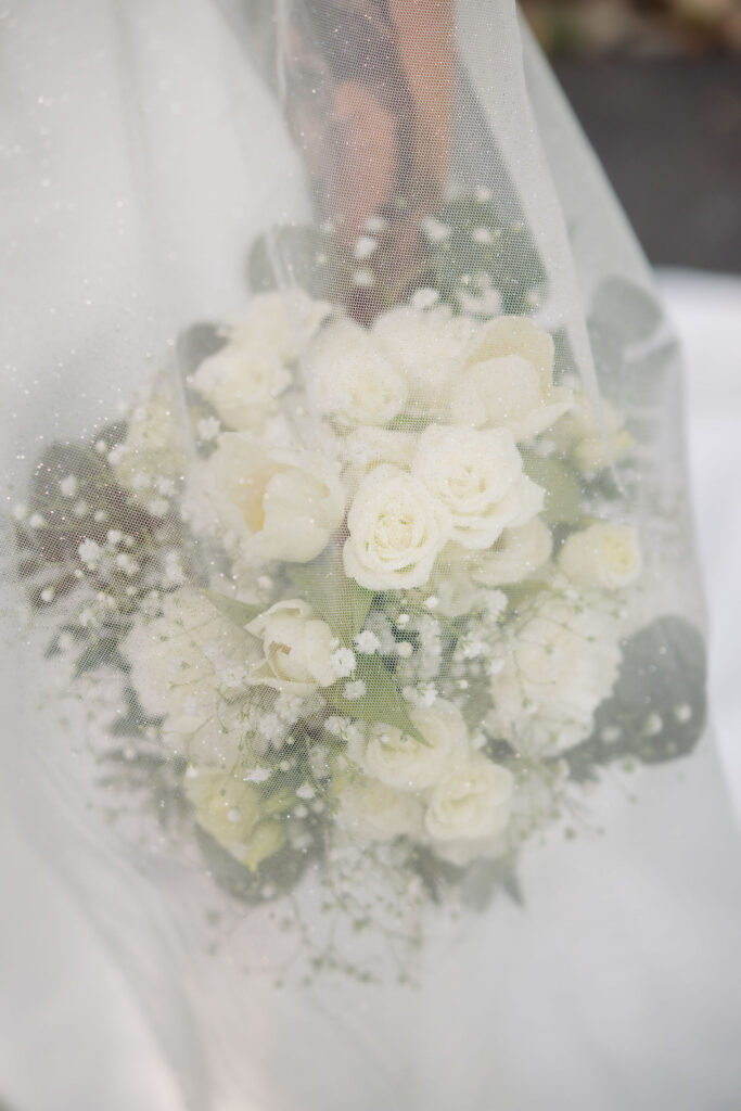 Close-up of a white rose and baby’s breath bridal bouquet softly photographed through the bride’s veil during a Gatlinburg elopement.