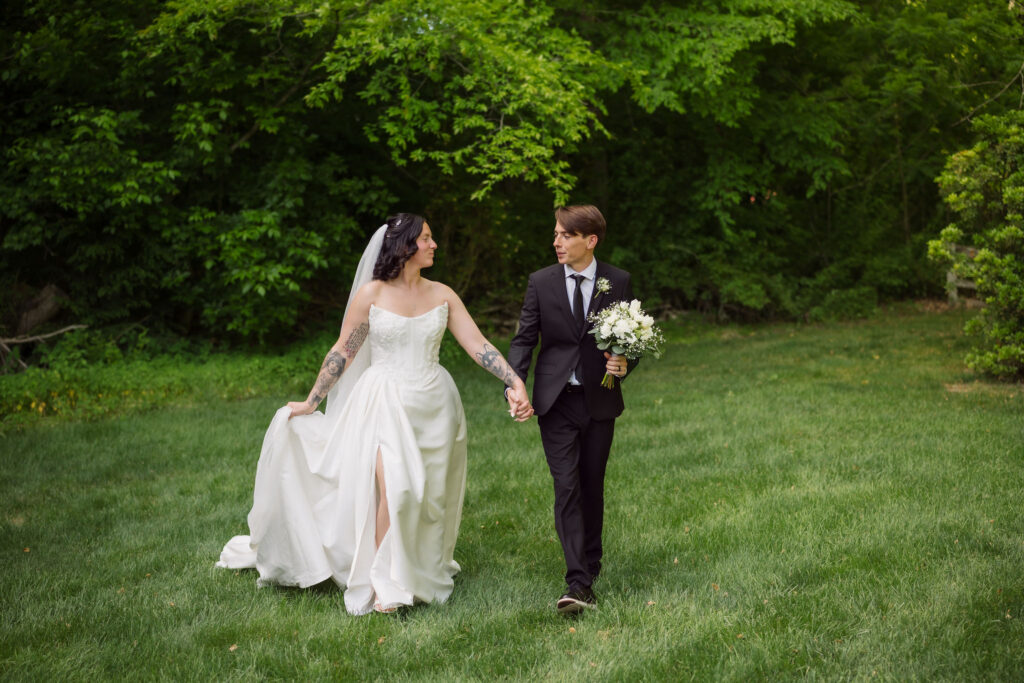 Smoky Mountain wedding venue with couple holding hands and walking together through a field near the treeline of the mountains