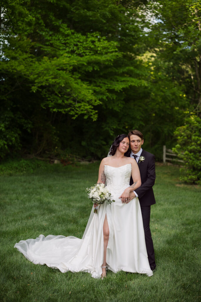 Couple eloping to Gatlinburg pose together on a lawn at a Gatlinburg wedding chapel and smile with their heads together.