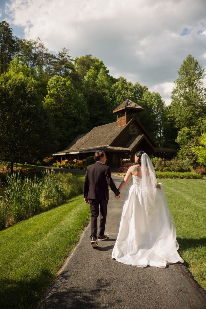 Newlyweds walk hand in hand toward the Little Log Chapel in Gatlinburg, a rustic woodland setting among Gatlinburg wedding venues and Gatlinburg chapels.
