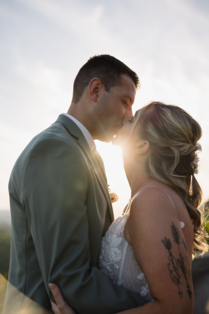 Newlyweds kiss in warm sunset light during their Gatlinburg elopement, framed by the mountain scenery along Foothills Parkway.