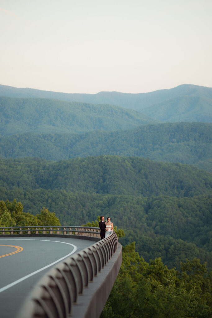 Bride and groom stand along a sweeping curve of Foothills Parkway with layered Smoky Mountain views surrounding their Gatlinburg elopement.