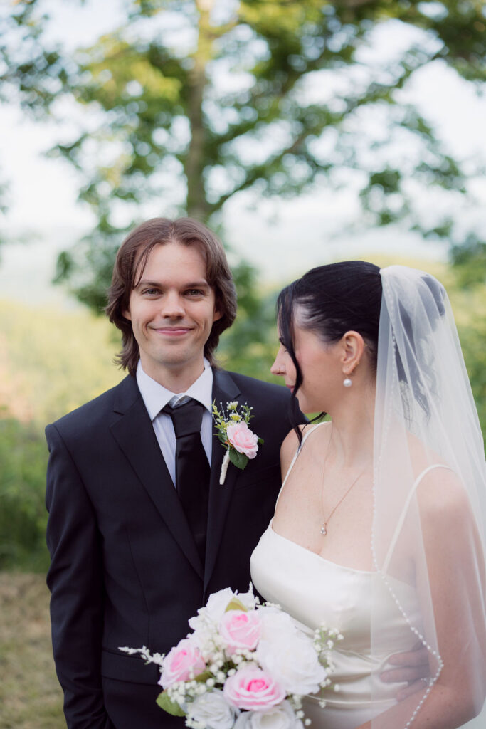 Close portrait of the newlyweds with the bride’s pink and white bouquet, photographed by a Gatlinburg wedding photographer at a mountain overlook.