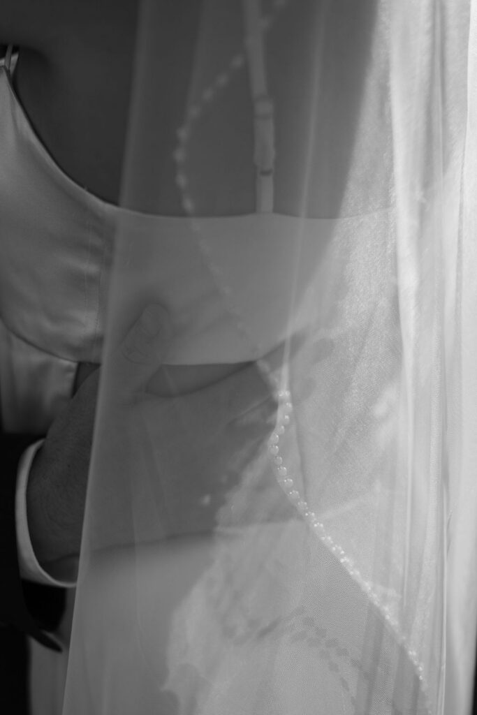 Black-and-white close-up of the bride and groom embracing beneath her sheer veil while eloping to Gatlinburg.