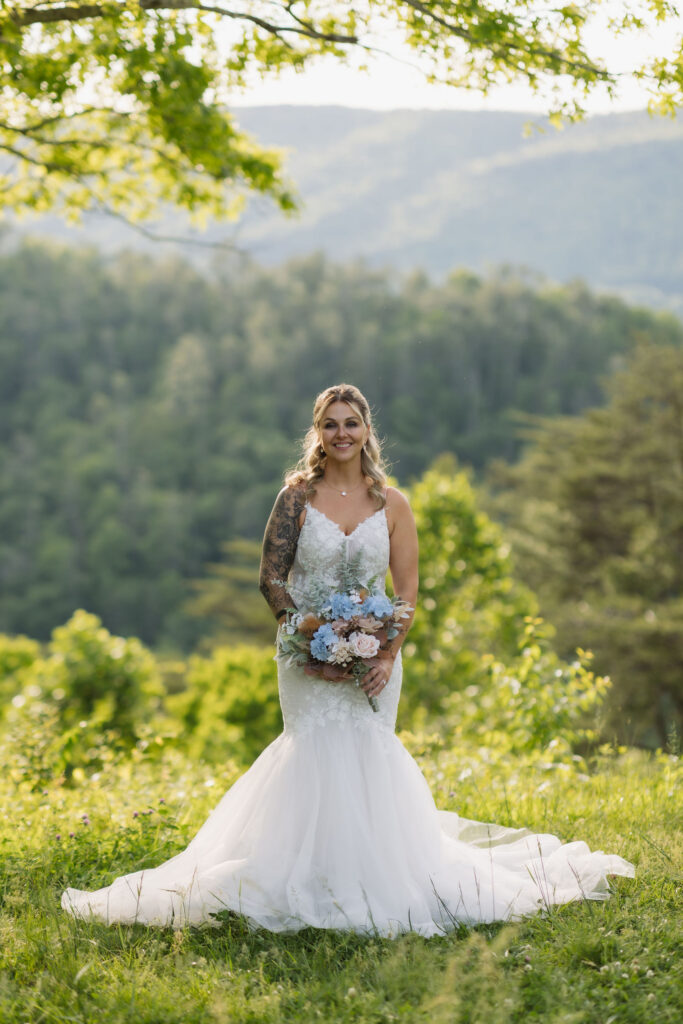 Bride poses with a pastel bouquet and lace wedding gown against layered mountain views during her Gatlinburg elopement.