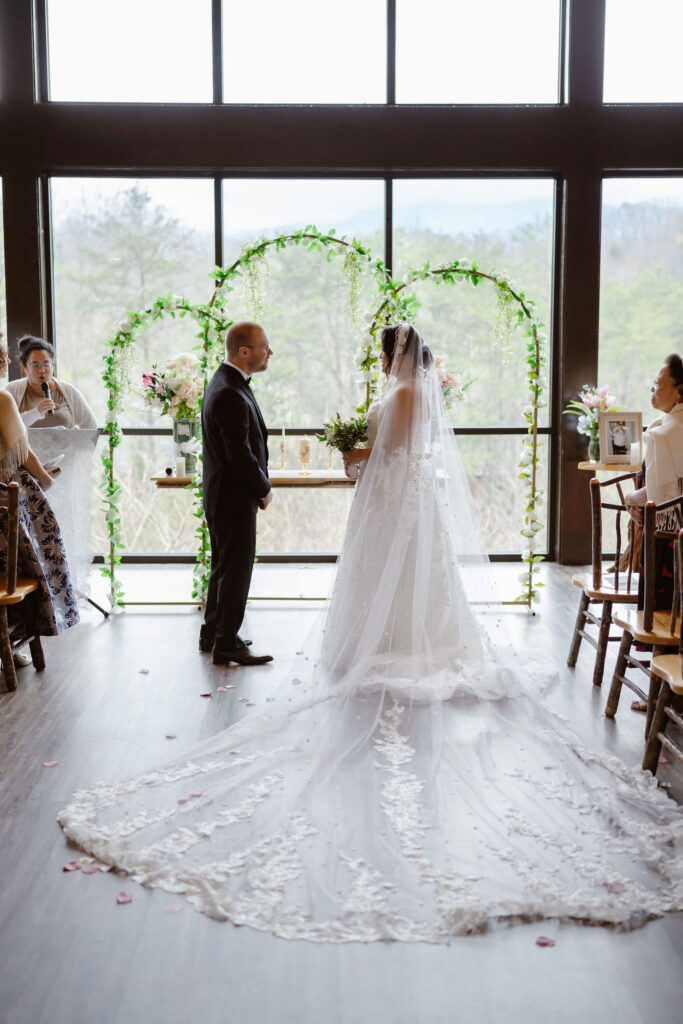 Bride and groom exchange vows during their Wild Briar Lodge Wedding, with a floral ceremony arch and mountain views creating an intimate setting for eloping to Gatlinburg.