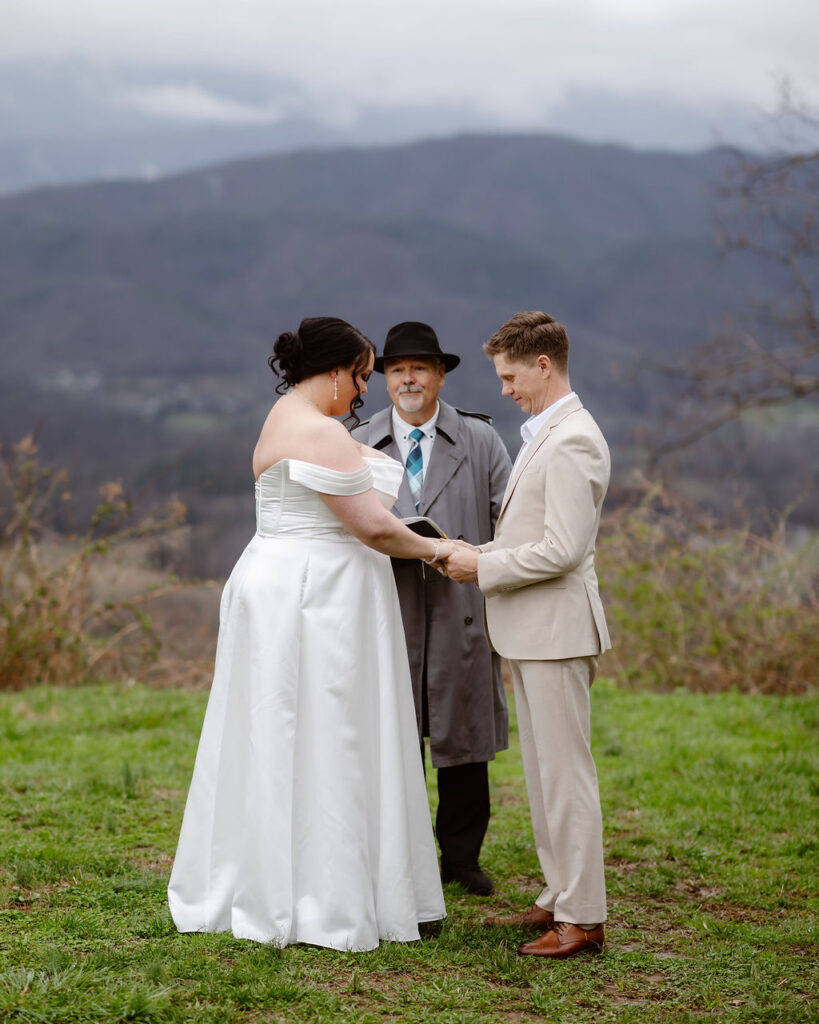 Couple exchanging vows with an officiant while eloping to Gatlinburg, surrounded by mountain views along foothills parkway.