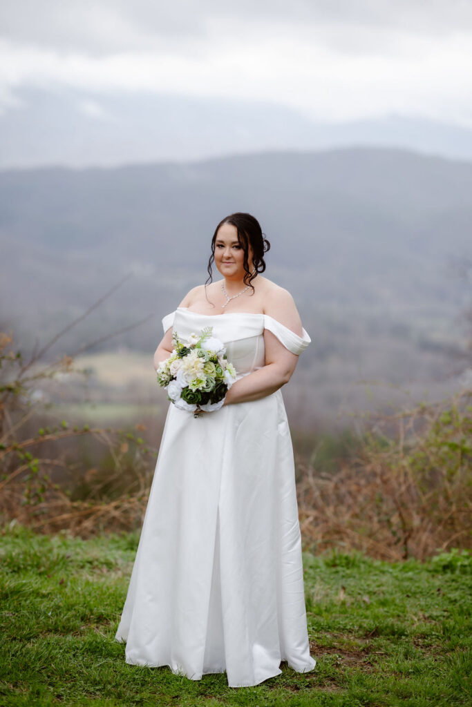 Bride holding a white and green bouquet with mountain views while eloping to Gatlinburg at foothills parkway.