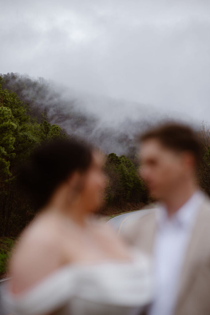 Fog drifts over the Smoky Mountains as a newlywed couple stands together while eloping to Gatlinburg at foothills parkway.