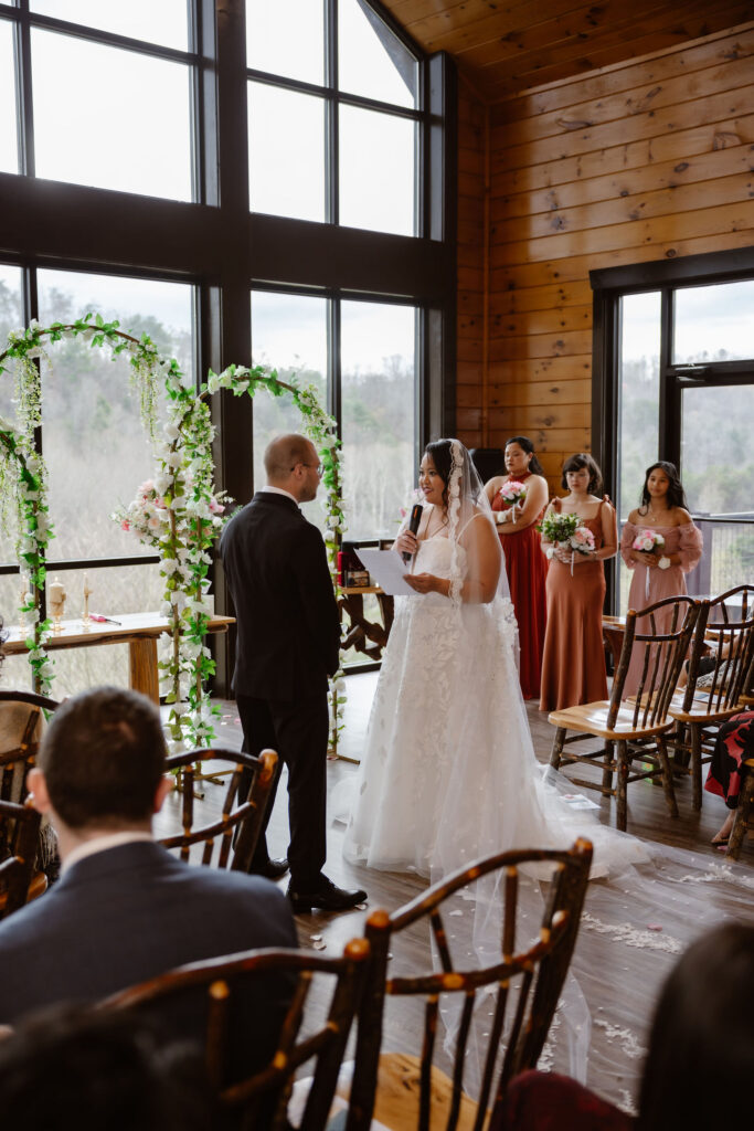 Bride reads her vows to the groom at a Wild Briar Lodge Wedding surrounded by family and floral décor, showcasing the intimate experience of eloping to Gatlinburg.