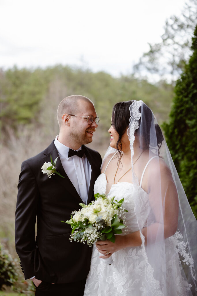 Newlyweds smile at each other while holding a bouquet after their Wild Briar Lodge Wedding, capturing a romantic portrait inspired by eloping to Gatlinburg.