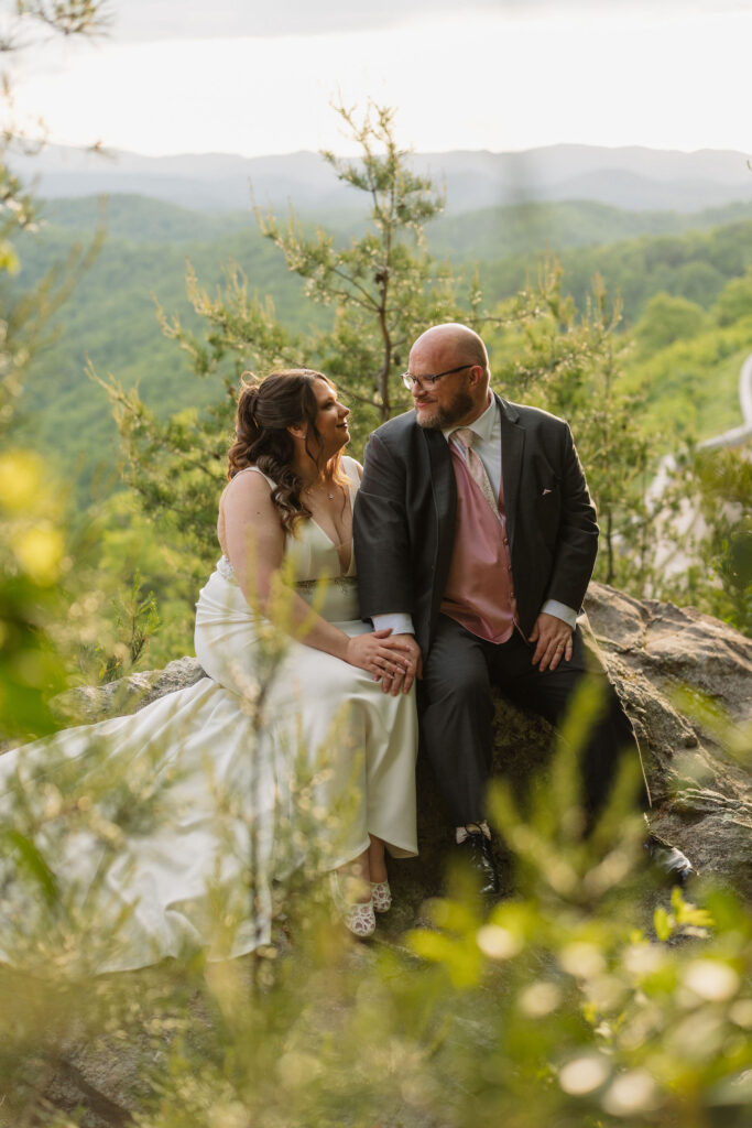 Newlyweds sit together on a scenic overlook along Foothills Parkway, soaking in the mountain views while eloping to Gatlinburg.
