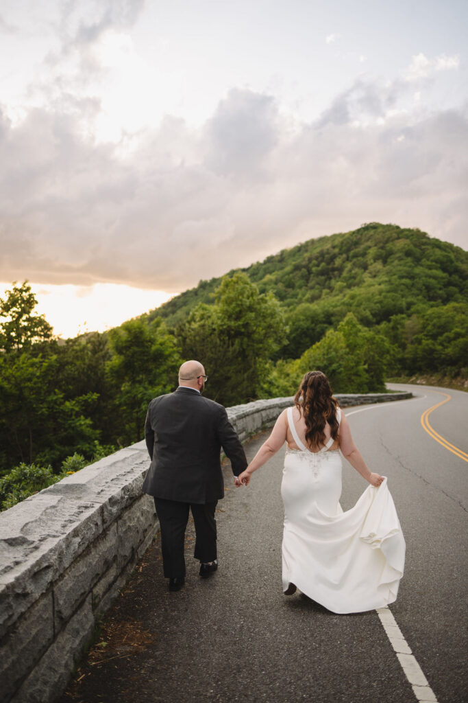 Newlyweds walk hand in hand along Foothills Parkway, surrounded by Smoky Mountain scenery during their unforgettable experience eloping to Gatlinburg.