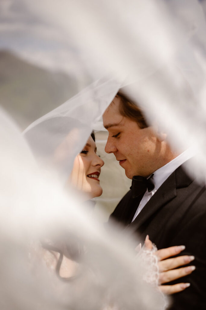Bride and groom share a quiet moment beneath the wedding veil in Cades Cove, capturing the romance of eloping to Gatlinburg.