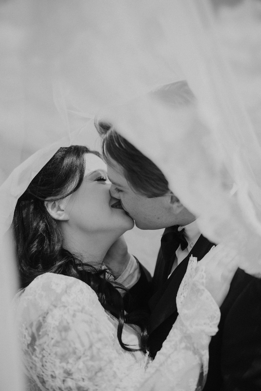 Bride and groom share a kiss beneath the veil in Cades Cove, capturing an intimate moment for couples dreaming of eloping to Gatlinburg.