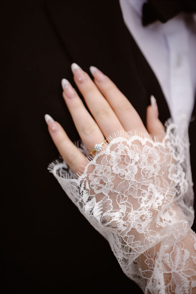 Close-up of a bride's engagement ring resting on the groom's suit, showcasing wedding details from a Cades Cove celebration while eloping to Gatlinburg.
