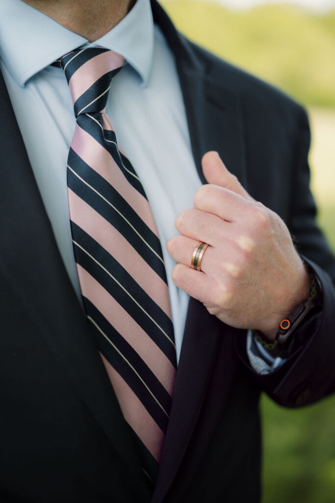 Close-up of the groom’s wedding band, striped tie, and dark suit, photographed by a gatlinburg photographer following an intimate mountain elopement ceremony.