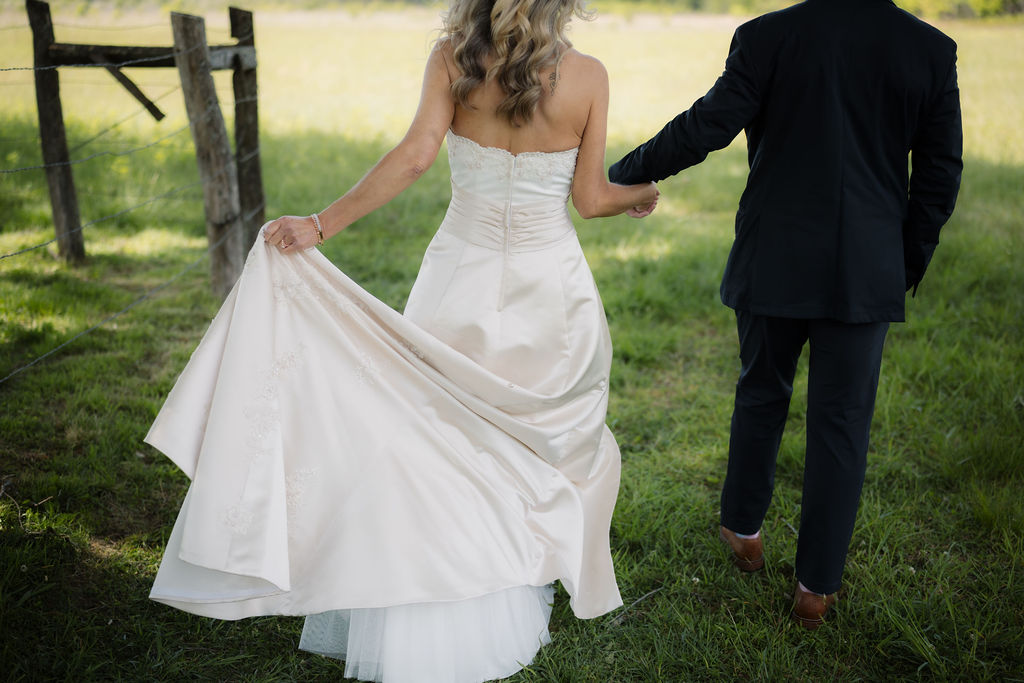 Bride lifts the train of her wedding gown while walking hand in hand with the groom, captured by a gatlinburg photographer during their mountain elopement.