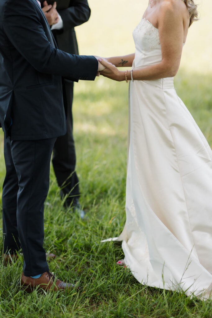 Close-up of a bride and groom holding hands during their ceremony, a candid detail captured by an elopement photographer while eloping to gatlinburg.