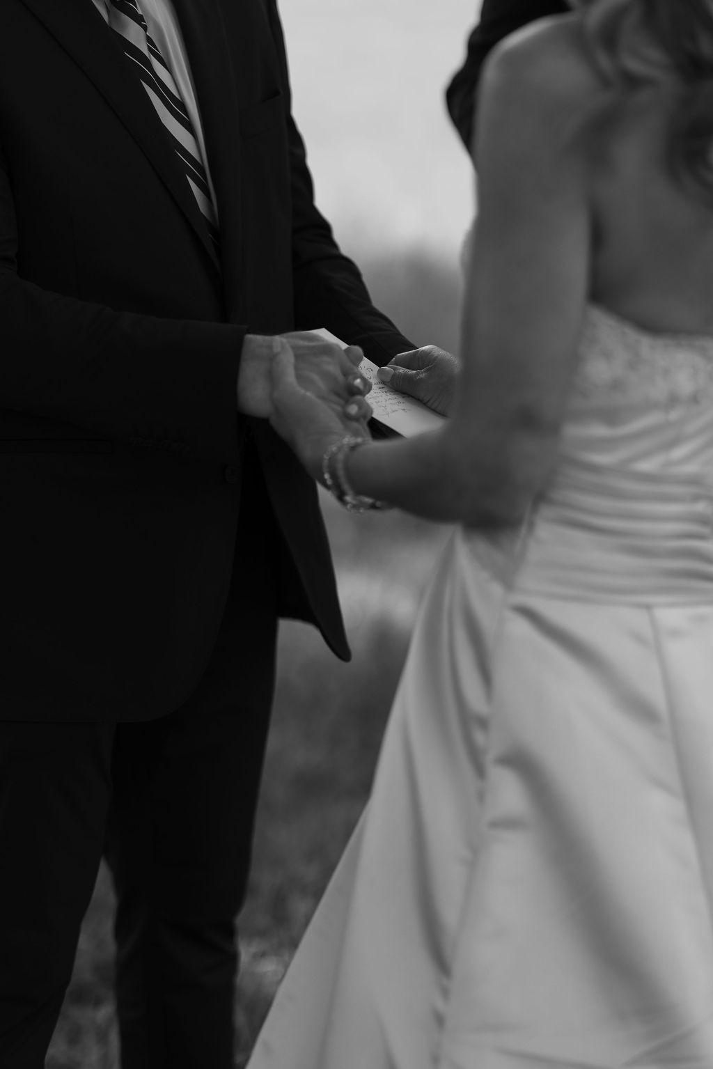 Bride and groom hold hands and exchange handwritten vows during their Gatlinburg Elopement Ceremony, captured in an intimate black-and-white photograph.