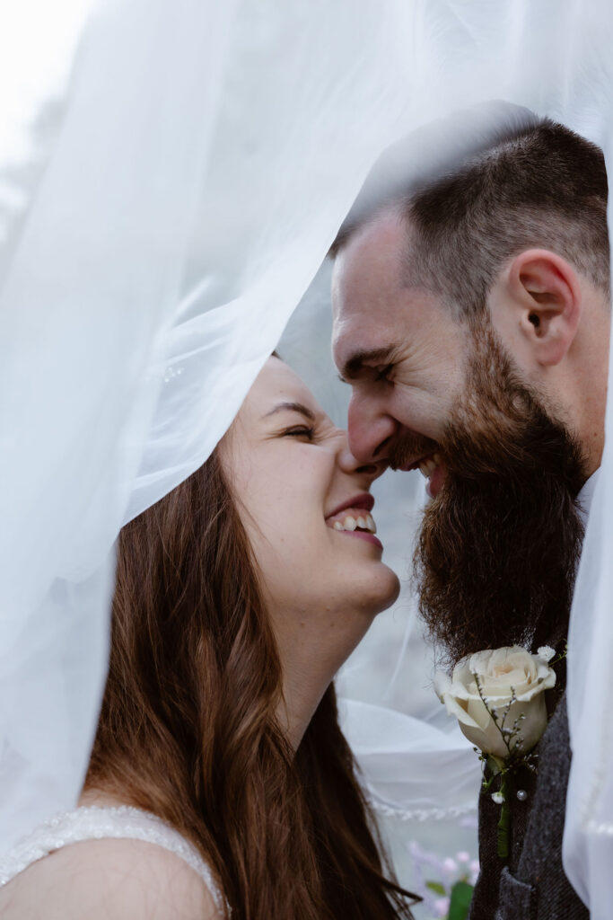 Close-up portrait of bride and groom smiling beneath her veil during their gatlinburg elopement.
